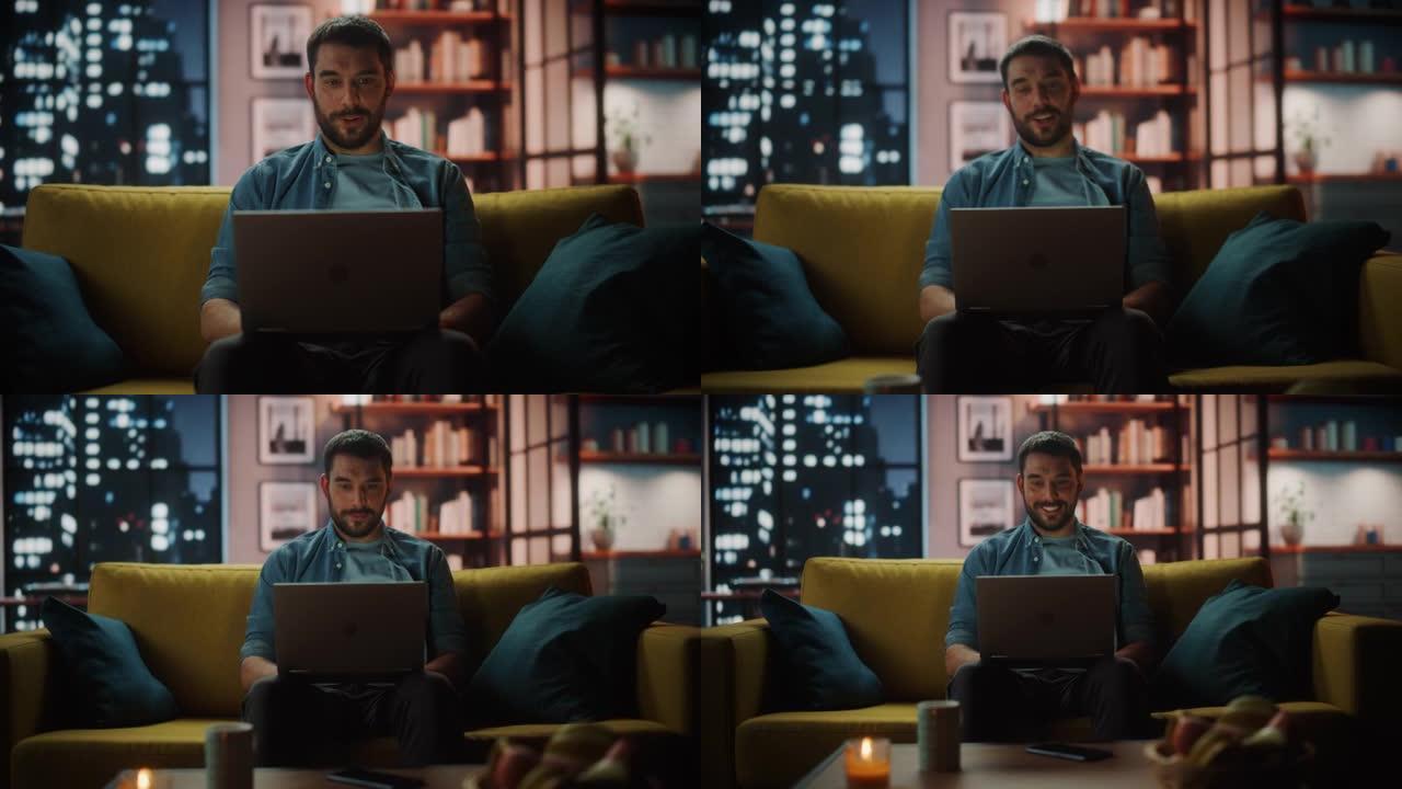 晚上，英俊的白人男子坐在黑暗舒适的客厅的沙发上，在笔记本电脑上的视频电话会议上交谈。自由职业者在家工