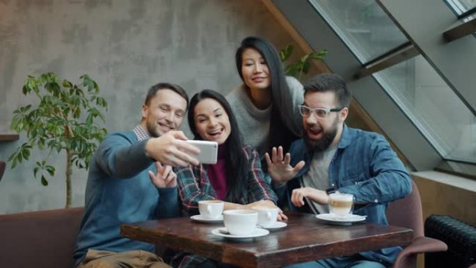 一群朋友在咖啡馆里自拍，摆出有趣的面孔和手势，为智能手机相机摆姿势