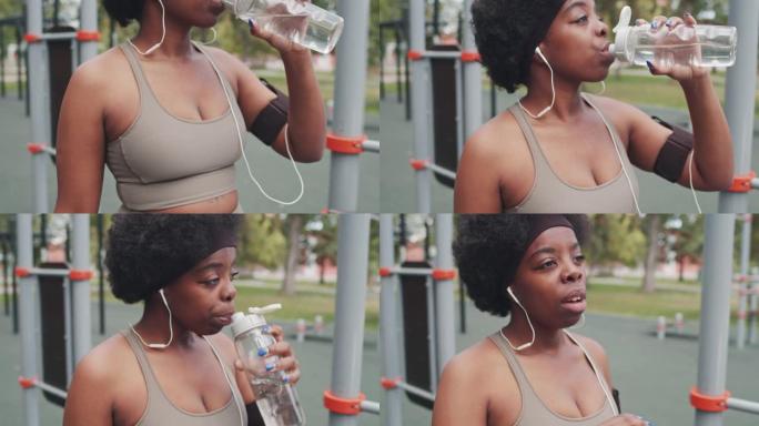 疲惫的黑人女运动员在户外喝水