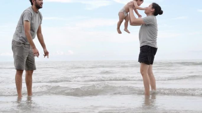 快乐的亚洲父亲，母亲和宝贝儿子在沙滩上学习日落大海的乐趣。假期