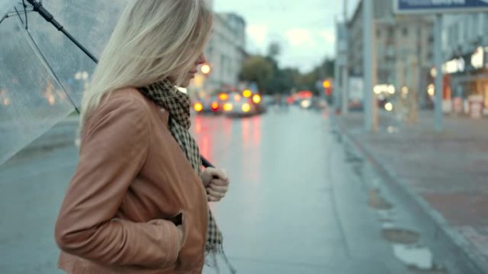 特写女人在雨天城市下多风的秋天天气里用开伞行走。时尚女性享受户外秋水滴城市生活背景。漂亮的眼睛女士感