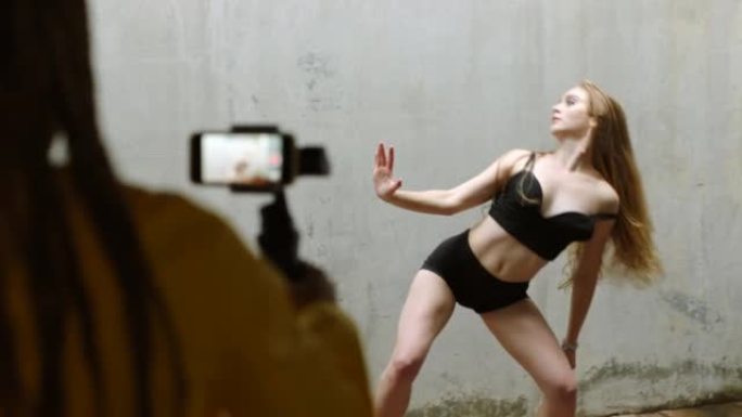 女性有影响力的舞者在直播中跳舞，这是一部为社交媒体网络和在线平台制作视频内容的手机。5g技术非常适合