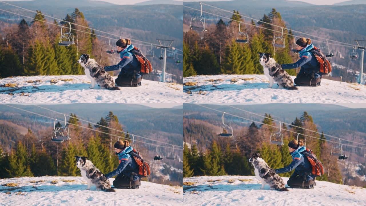 SLO MO年轻女子抱着她的狗在山顶上，可以看到滑雪缆车
