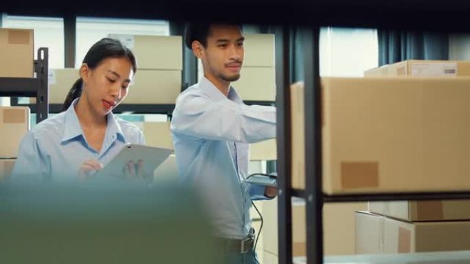 亚洲商业伙伴男人拿着笔记本电脑和扫描仪女孩穿正式衬衫拿着平板电脑讨论库存在线库存数据交付客户在仓库。