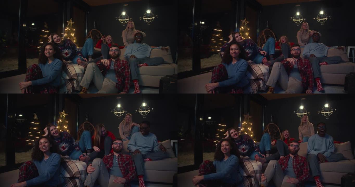 快乐的年轻微笑的多民族朋友在圣诞派对慢动作的舒适沙发上看电视电影