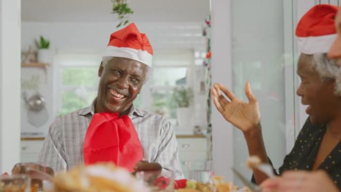 戴圣诞老人帽子的多代家庭一起在家吃圣诞大餐