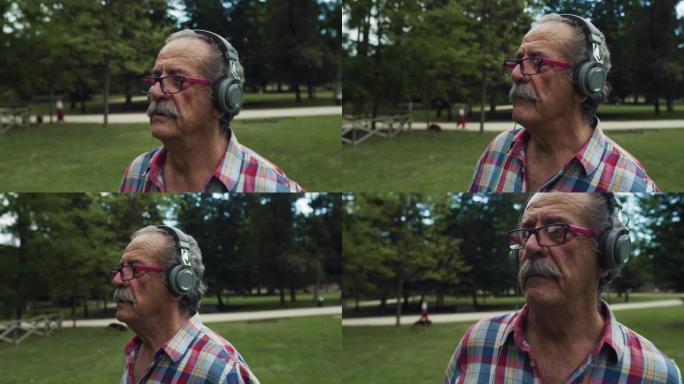 一个活跃的老人在绿色公园散步，戴着耳机听音乐的肖像。快乐开朗的老年男性，穿着一件彩色衬衫享受生活，伴