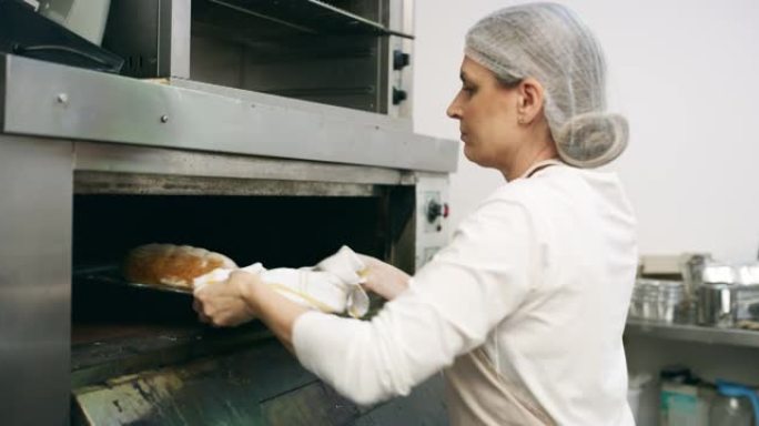 一个成熟的面包师在面包店从烤箱中取出面包的4k视频片段
