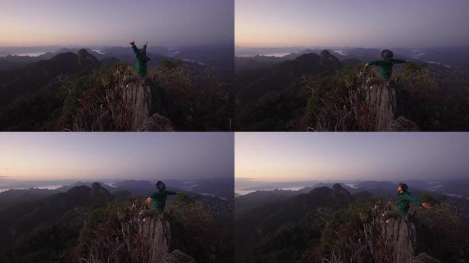 女人在山顶上徒步旅行，举手庆祝成功
