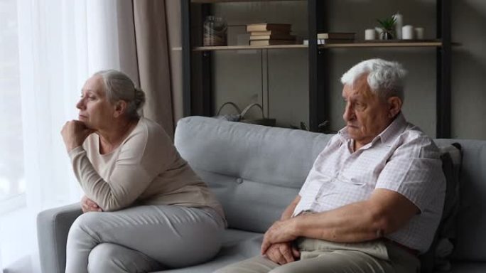 悲伤的怨恨老年家庭夫妇分别坐在沙发上