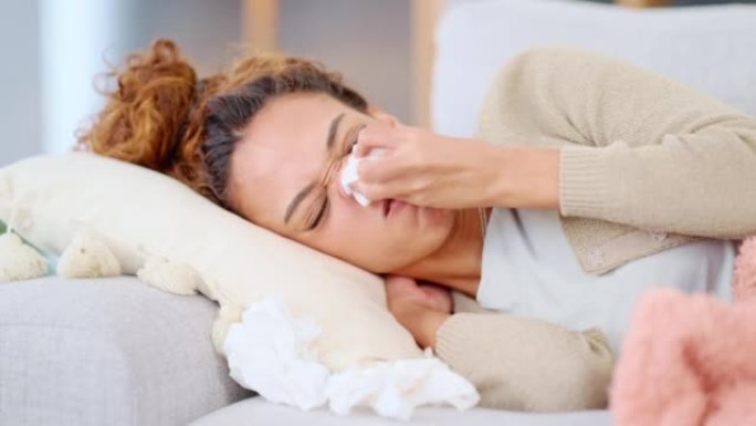 生病的妇女在家中患流感或感冒。一位患有鼻窦不适的年轻女性躺在她家的沙发上。一位不适的女士躺在沙发上发