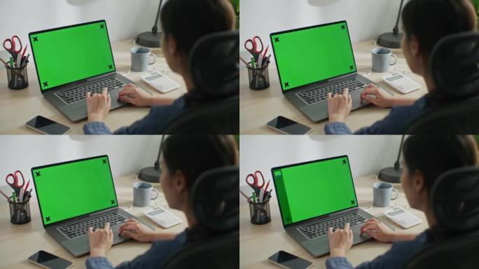 女人在绿色屏幕的笔记本电脑键盘上打字