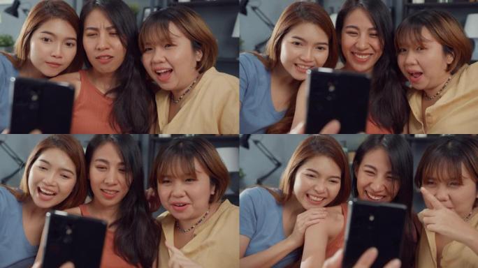 一群年轻的亚洲女性感到快乐的微笑放松在家里的客厅使用智能手机视频通话。开朗的室友女士视频会议与朋友，