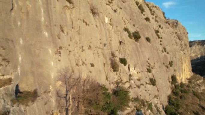 空中: 靠近阳光普照的攀岩墙飞行并接近男性登山者