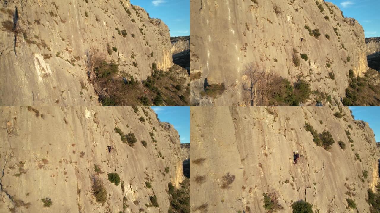 空中: 靠近阳光普照的攀岩墙飞行并接近男性登山者