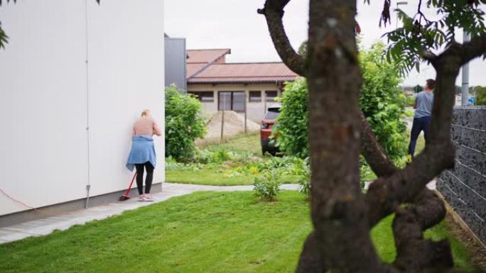 女人在后院扫荡，而男人在花园里割植物叶子