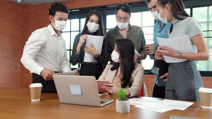 4K UHD多莉向前放大: 商务团队在办公室会议室集思广益。作为新的正常生活方式，他们戴口罩可以降低