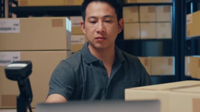 特写亚洲商人使用条码机扫描纸盒中的客户数据，并在笔记本电脑中输入注册在线信息订单详细信息，以便在仓库