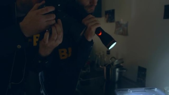 两名FBI探员拿着手电筒和照相机在一间黑屋子里检查犯罪分子的巢穴中的物证