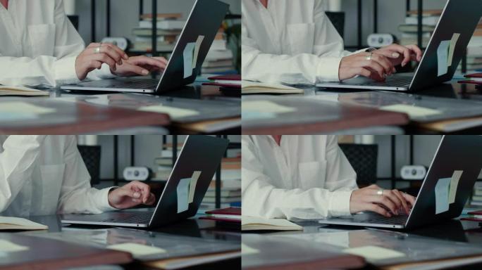 在现代轻便的办公桌上使用笔记本电脑打字信息，用优雅的戒指特写女性双手。在线工作概念