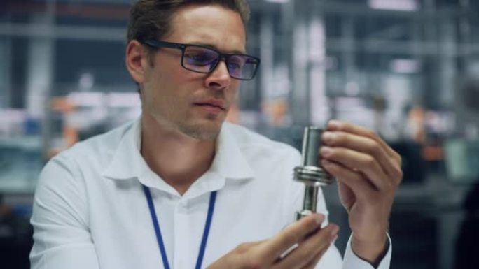 在汽车装配厂的办公室里，年轻英俊的工程师戴着眼镜在制造金属零件的特写肖像。工业产品设计师在生产前检查