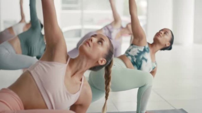 妇女在健身工作室的健身课上练习瑜伽。在小组训练期间，多样化且专注的活跃女性伸展和弯曲以执行姿势和体式