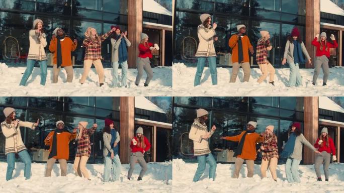 寒假。一群快乐有趣的多民族年轻朋友在阳光明媚的雪屋露台慢动作一起跳舞。
