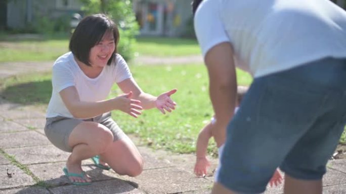 亚洲华裔家长教男婴学第一步清晨在公园散步