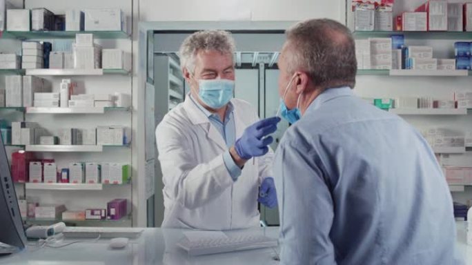 电影镜头男药剂师带着医用口罩在药房对男患者进行冠状病毒鼻咽拭子试验。概念:covid-19、保护、安