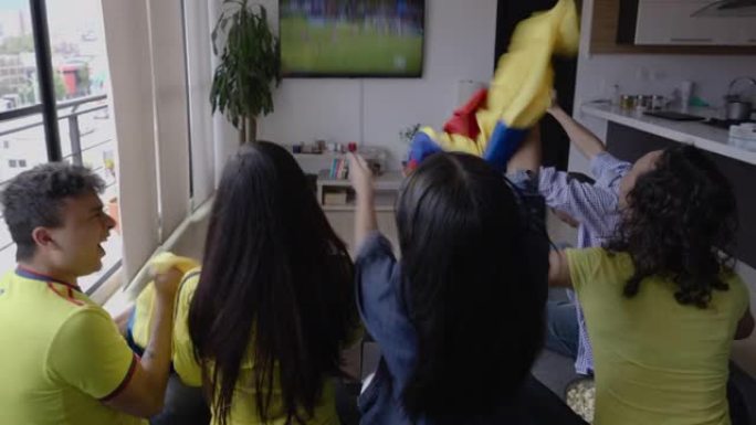室友们坐在沙发上看足球比赛，庆祝进球