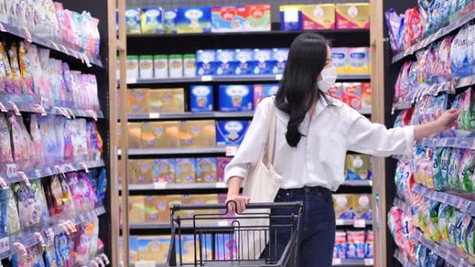 在新型冠状病毒肺炎冠状病毒流行期间，25岁的亚洲年轻女性戴着防护医用口罩在超市购买基本必需品。她穿过