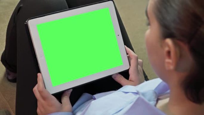一位年轻的女商人正在使用她的数字智能平板电脑。在和公司的其他同事见面之前，她正在看她的文件。她穿着非