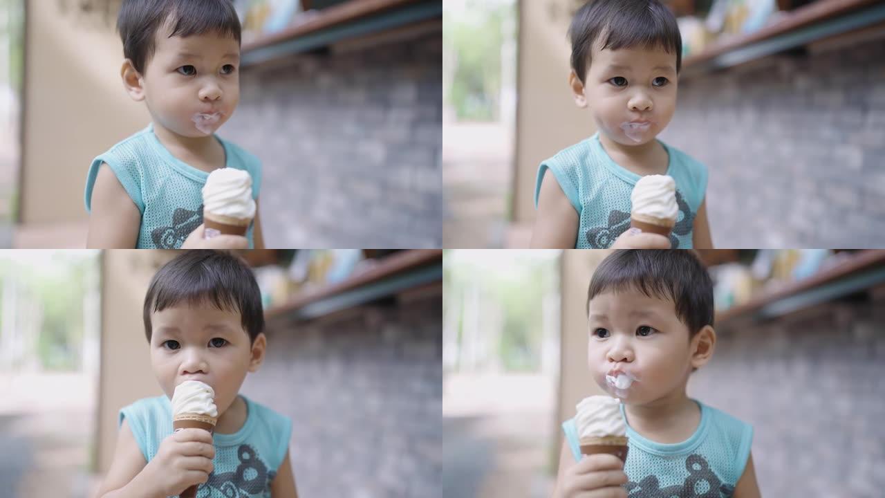 亚洲可爱的蹒跚学步的男孩，年龄2岁，在炎热的夏日户外吃美味的冰淇淋，同时吃脏脸。孩子在假期享受甜点。