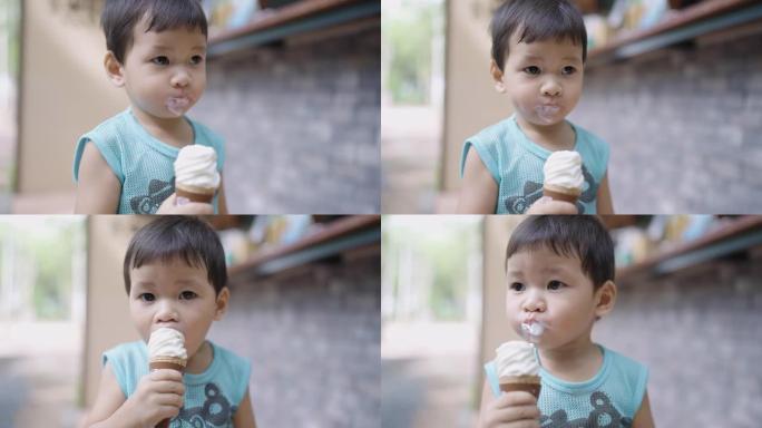 亚洲可爱的蹒跚学步的男孩，年龄2岁，在炎热的夏日户外吃美味的冰淇淋，同时吃脏脸。孩子在假期享受甜点。