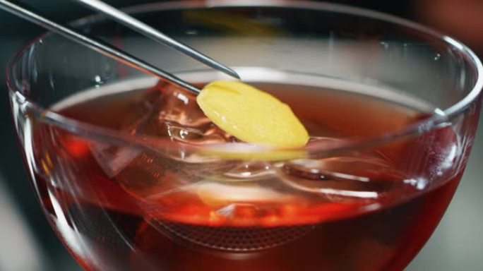 专业调酒师的Macro正在酒吧或迪斯科舞厅为顾客提供带有冰块的精英酒精鸡尾酒。