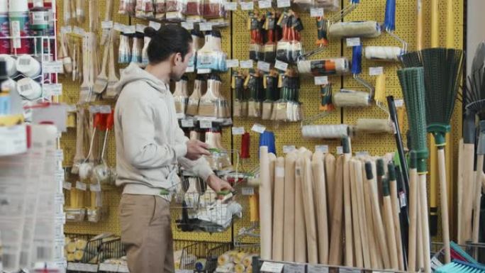 男人在商店购买画笔和油漆滚筒