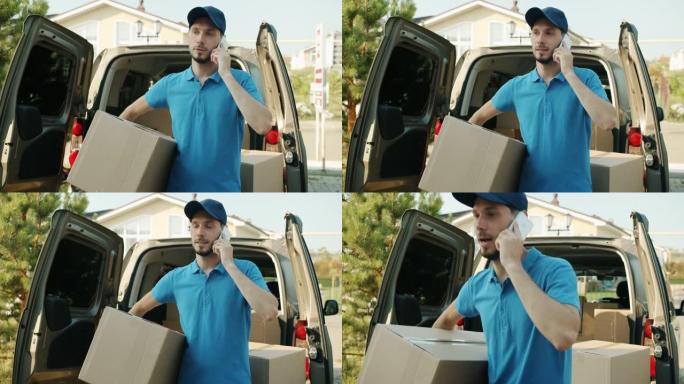 送货员在手机上聊天，拿着包裹站在外面的商用货车附近