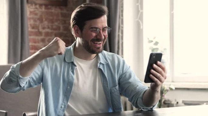 手持智能手机的男子收到短信阅读好消息庆祝成功
