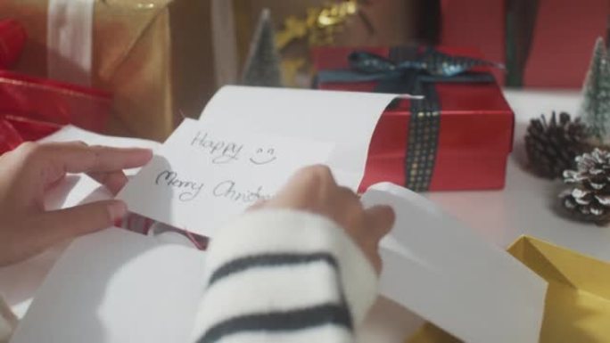 女孩双手包装礼物礼品盒的特写桌子上的冬季圣诞装饰品。