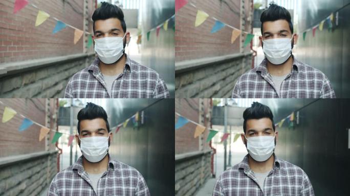 城市户外站立着戴着医用口罩的严肃阿拉伯男子的肖像
