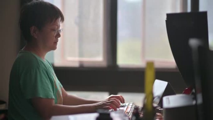 背光侧视图亚洲中国中年妇女在家打字电脑键盘