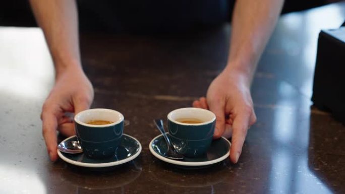 咖啡师在咖啡馆里提供两个温暖的咖啡杯的特写镜头