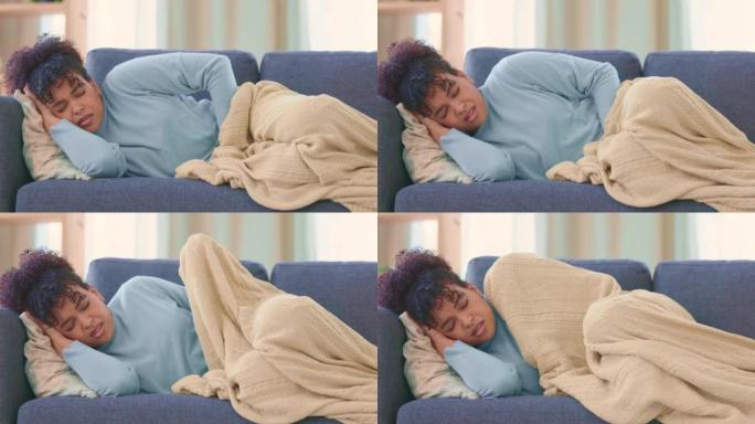 女人躺在家里的沙发上遭受PMS疼痛。患有慢性子宫内膜异位症的年轻女性在沙发上用毯子覆盖自己。在流产的