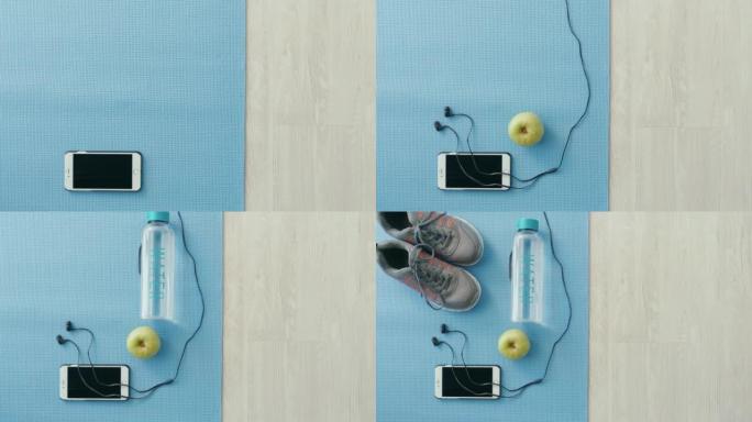 瑜伽垫和健身器材的上方视图。手机，耳机和健身器材，在空荡荡的工作室里放空复制空间。在常规运动中通过训