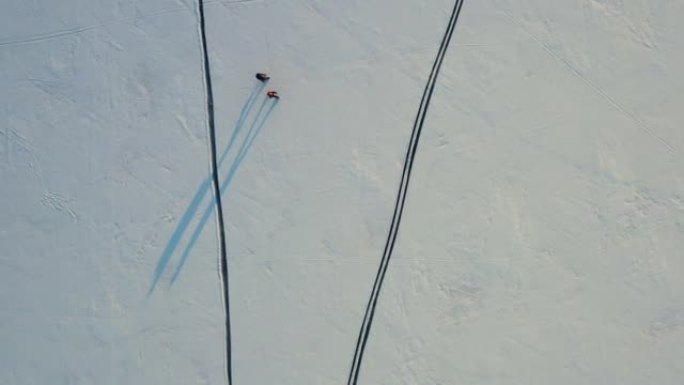 两个背着背包走过雪场的旅行者的俯视图