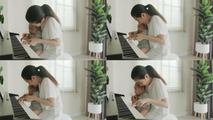 单身母亲抱着刚出生的男婴手在家里弹钢琴。她教她可爱的孩子演奏古典乐器。