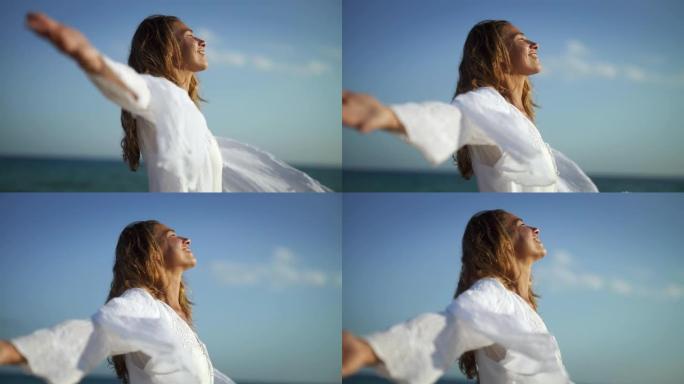 一位年轻无忧无虑的女性游客的真实特写镜头在风景秀丽的海景上张开双臂，感到自由和深呼吸