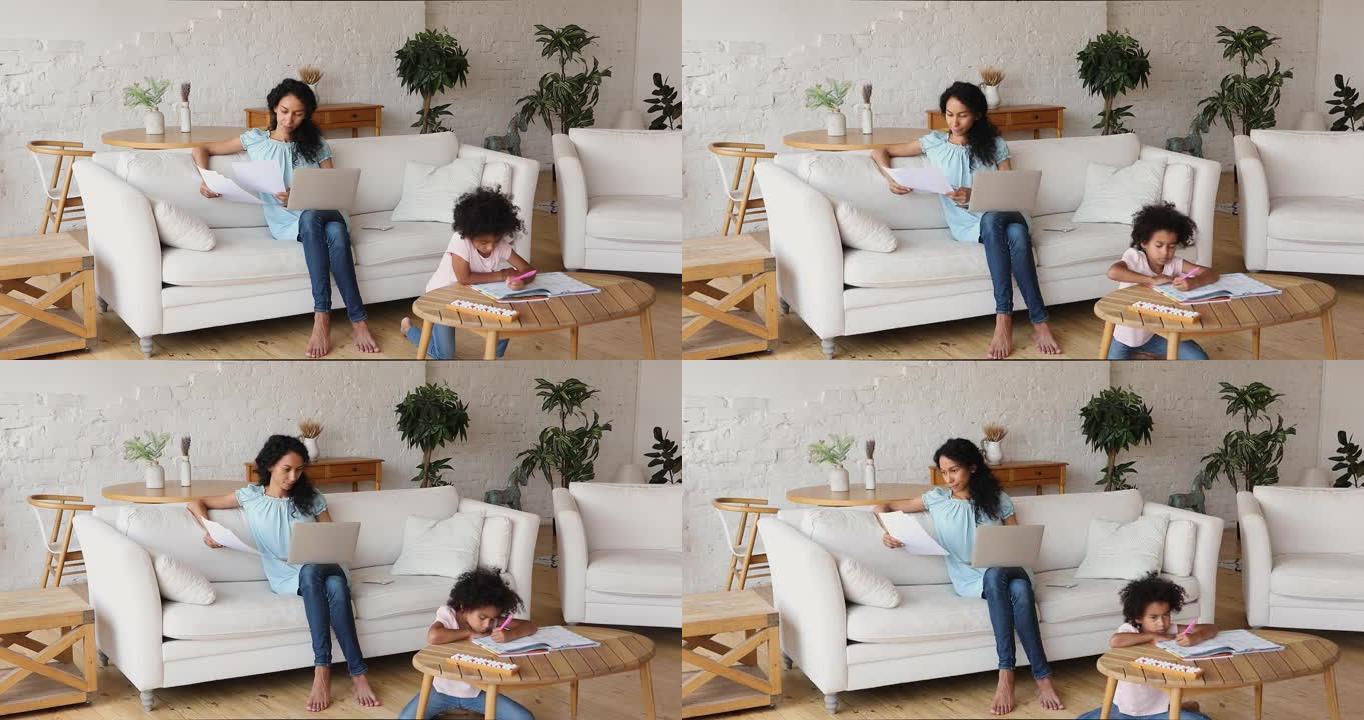 远距离工作的非洲妇女使用笔记本电脑，她的小女儿绘画