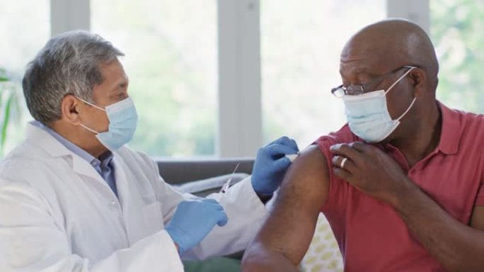 男医生戴口罩在家给非洲裔高级男子接种疫苗