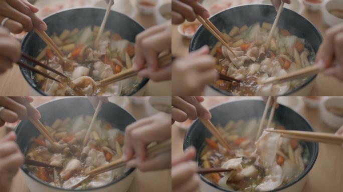 用筷子在火锅里煮肉的手的俯视图。
